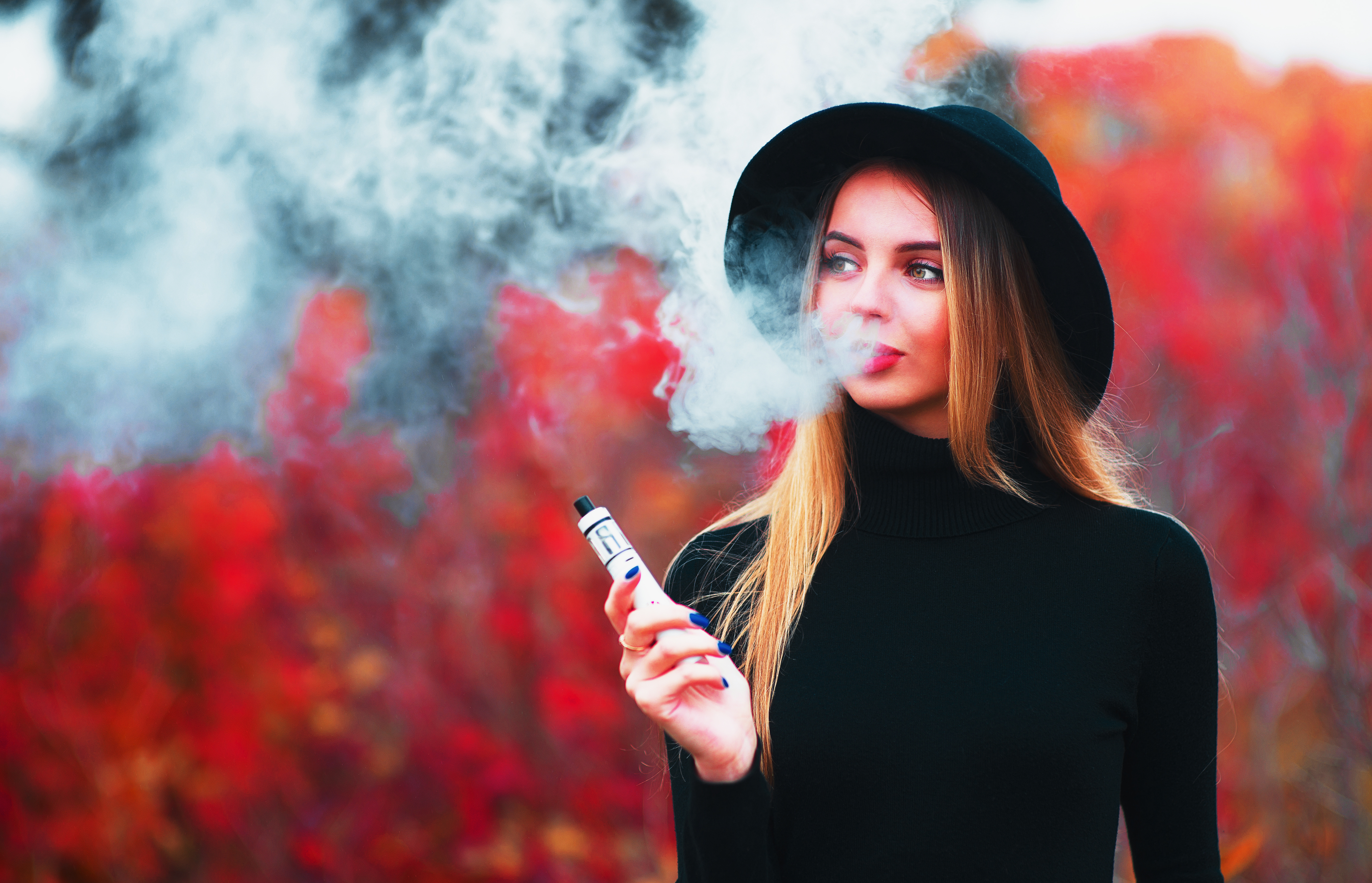 Entspannte Frau im Herbst dampft CBD Vape praktisch für unterwegs und zwischendurch